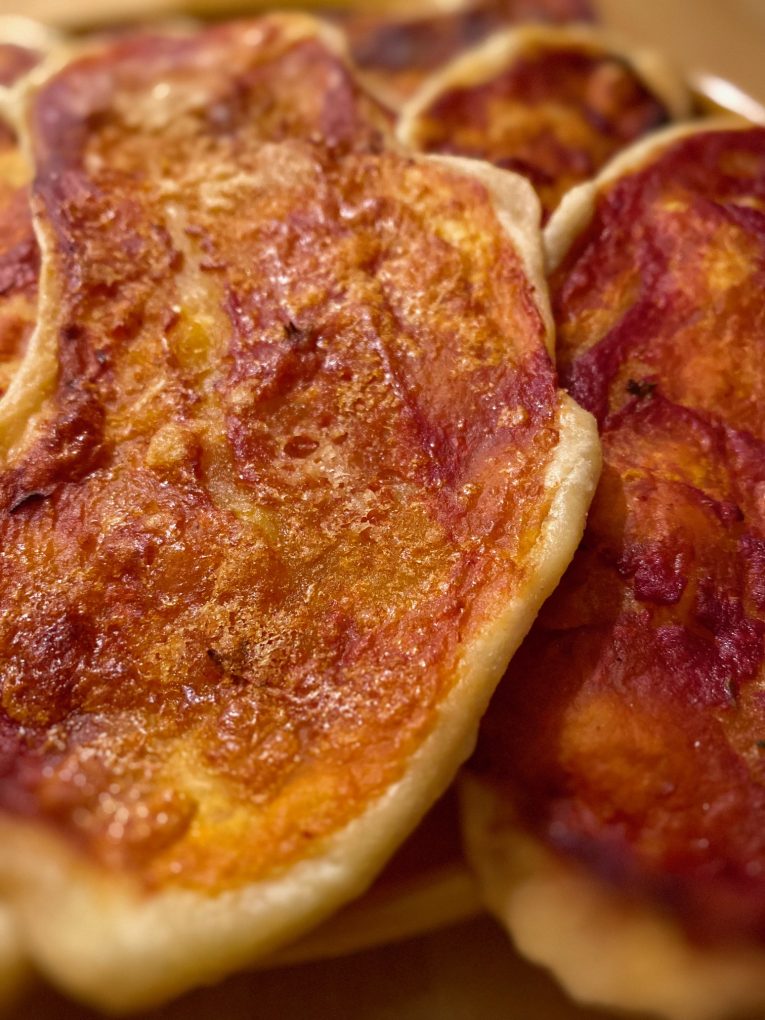 Golden, crispy semolina pizza tongues topped with tomato and oregano