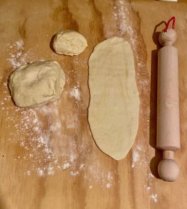 Thin semolina pizza tongues rolled out on a floured surface