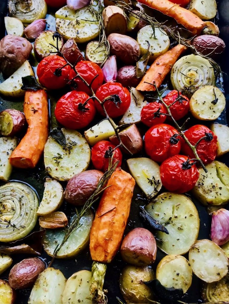 Roasted Mediterranean vegetables tray bake on baking tray with olive oil and herbs