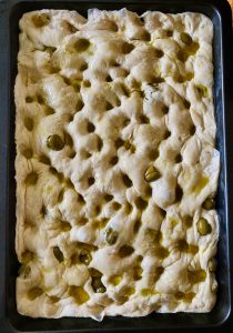 stretched focaccia dough with green olives added