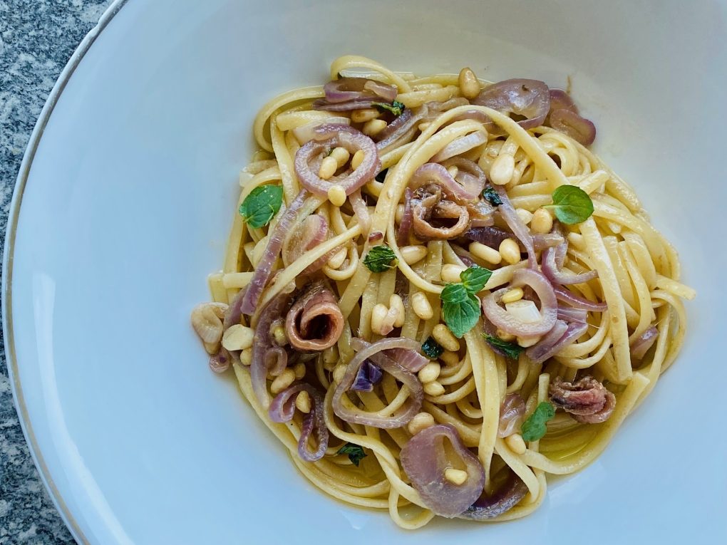 Pasta dish with red onion, anchovy, mint and pine nuts
